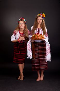 Young women in ukrainian clothes, with garland and round loaf