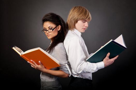 Two students are reading books on a black background