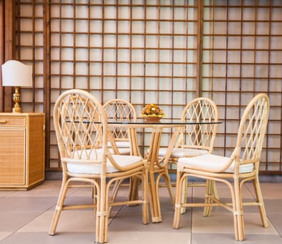 Glass table with wickler chairs in an elegant interior