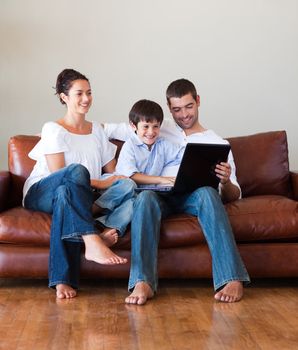 Parents and kid playing with a laptop on a couch at home