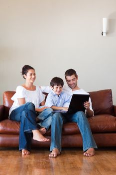 Parents and son playing with a laptop at home with copy-space