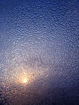 The image of droplets of water on glass and beam of sun