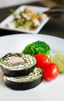 salmon ham sushi rolls and  fresh vegetables on white dish