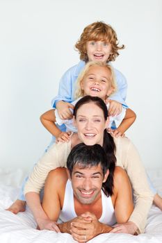 Cheerful family lying on a white bed
