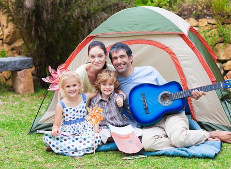 Happy family playing a guitar in a tent
