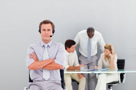 Businessman with a headset on in an office and with folded arms