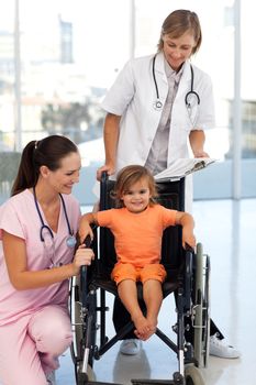 Doctors with a little girl sitting on a wheelchair at hospital