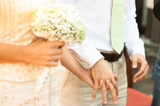 Close up of a bride and groom holding hands during wedding ceremony.
