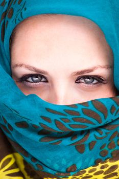 Beautiful Arab woman wearing blue scarf, stylish female close up face portrait, serious expression, stunning sensual beauty.