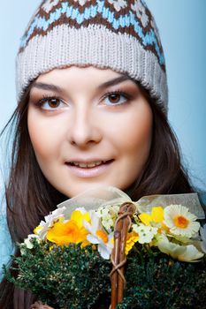 smiling woman in cap with basket of flowers on blue background