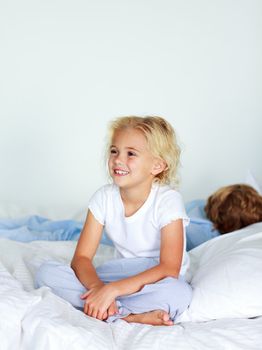Smiling blonde girl sitting on a big bed