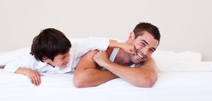Father and his son having fun on a bed at home