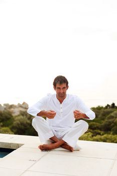 Attractive mature man doing yoga on the pool with copy-space