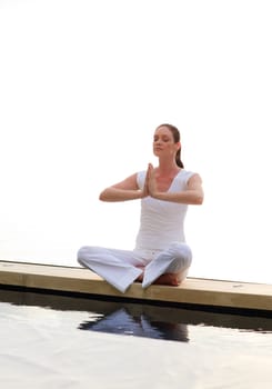 Woman doing yoga near the sea on the morning