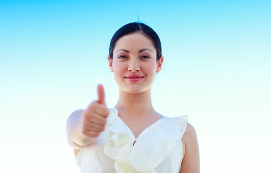 Smiling young businesswoman outdoors with thumbs up