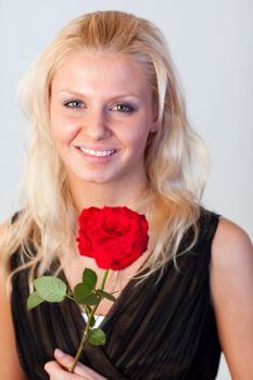 Portrait of an attractive woman with a red rose and smiling at the camera with focus on woman 