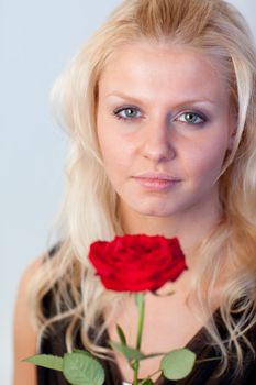 Beautiful blonde woman with a red rose looking at the camera with focus on woman