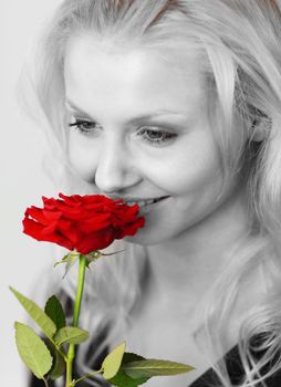 Close-up of an smiling woman in black and white smelling a red rose 