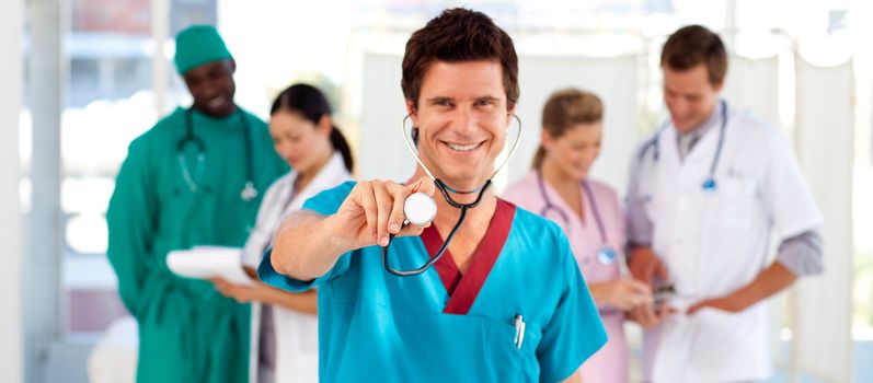 Friendly doctor with his team in the background in hospital