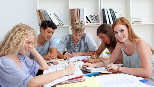 Smiling teenagers studying in the library. Concept of education