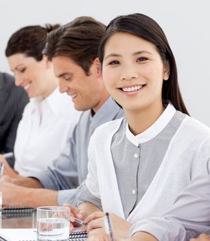 Smiling businesswoman in a meeting with her team looking at the camera