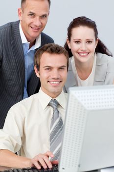 Smiling business people working together with a computer in the office