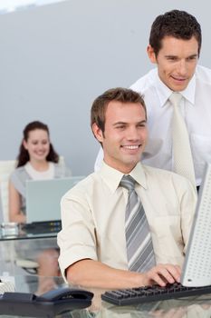 Smiling businessmen working together with a computer in a company
