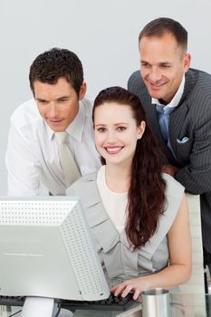 Smiling businesswoman and two businessmen using a computer in the office