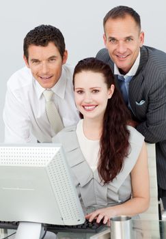 Smiling three business people using a computer in the office