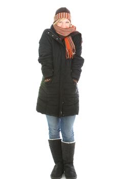 Young woman standing snuggling into the warmth of her warm winter clothing in boots, overcoat, hat and scarf