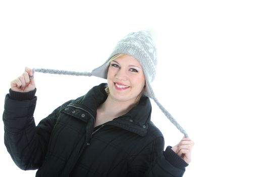 Playful woman in winter hat smiling happily and twirling the long pom poms on the ear flaps in her hands isolated on white Playful woman in winter hat smiling happily and twirling the long pom poms on the ear flaps in her hands isolated on white