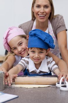 Smiling mother and children baking in the kitchen