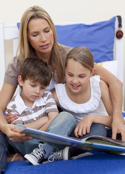 Mother reading a book with her children in bedroom