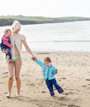 A young mother is playing with her childrens at the beach