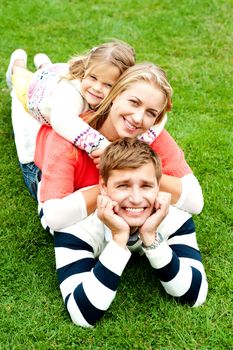 Husband, wife and child piled on each other. Father with cheeky expression