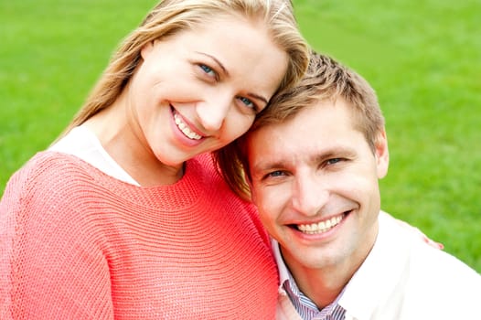 Close up shot of attractive love couple. Lush green lawn in the background