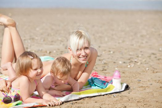 A laughing family lying at the beach and watching into the camera