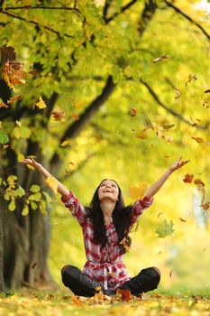 woman drop up leaves in autumn park