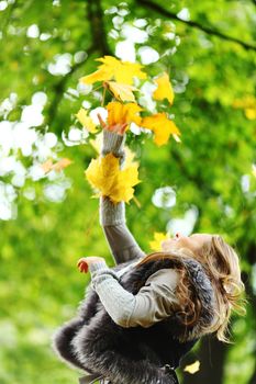 woman drop up leaves in autumn park