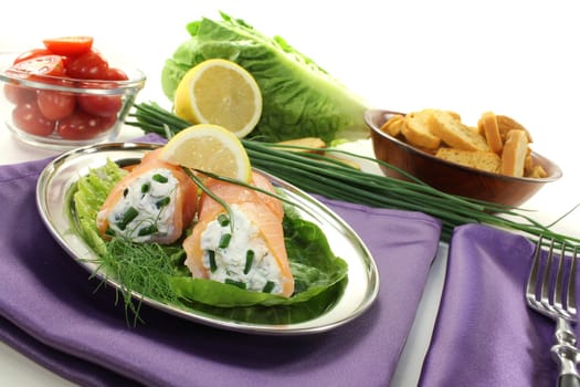 Salmon rolls with cream cheese and chives on a purple napkin