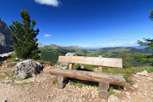 view of Gardena valley from Sassolungo mount with wooden bench, Italian Dolomites