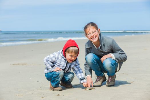 Adorable happy kids plaing with crab on the beach on spring day
