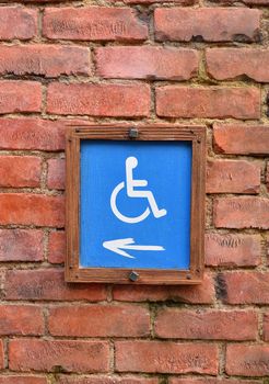 Wheelchair wooden sign on brick wall