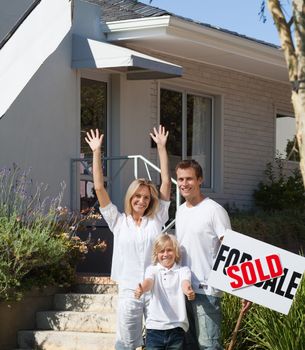 Father, mother and son in front of their new house in the sunshine