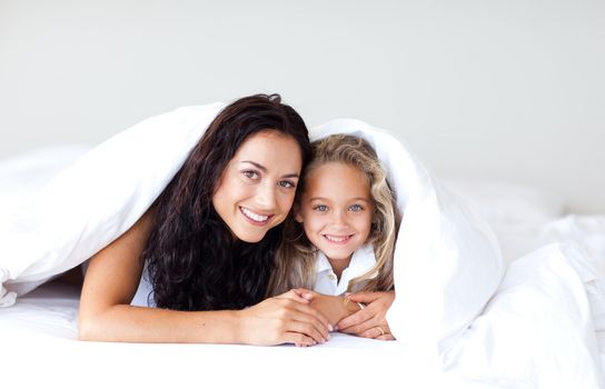 Young family lying on the bed smiling at camera