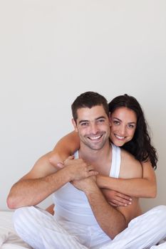 Handsome woman  hugging her attractive boyfriend sitting on a bed