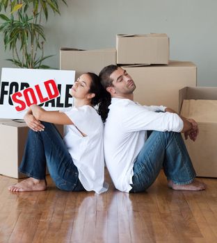 Happy young couple moving house relaxing on the floor