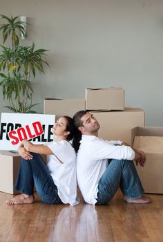 Young Couple relaxing after buying house sitting on the floor