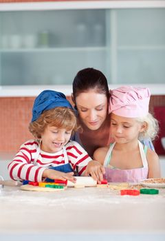 Children baking cookies for their mother in the kitchen