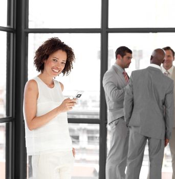 Cheerful Businesswoman holding a phone at workplace with his colleagues in the background